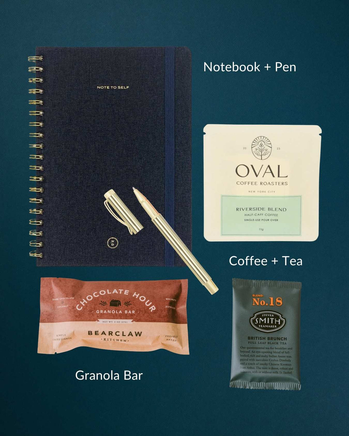 Dark blue linen notebook, gold pen, coffee pour-over, tea sachet, and granola bar arranged on a dark teal background.