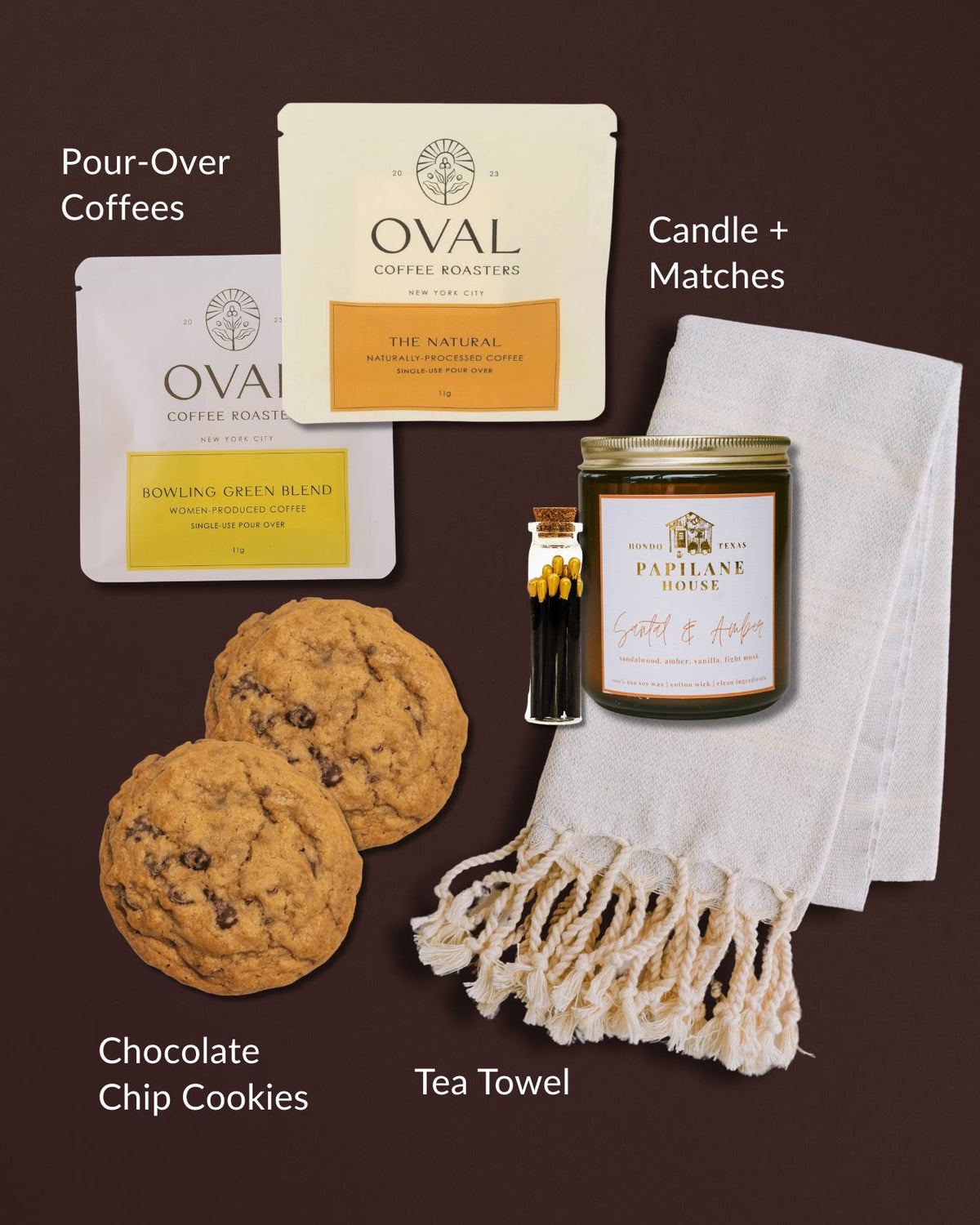 Gift set with two Oval coffee packets, chocolate chip cookies, a scented candle, matches, and a fringed Turkish hand towel.