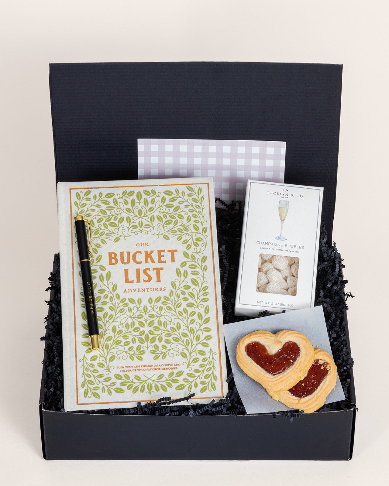 Adventures for Two gift box featuring a bucket list book, champagne bubbles, and heart-shaped pastry.
