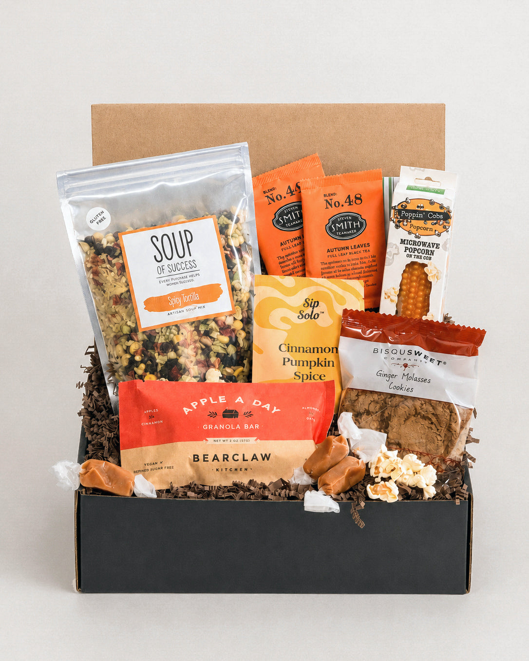 Fall gift box featuring spicy tortilla soup mix, autumn tea, popcorn, granola bars, ginger cookies, and caramels in a black box.