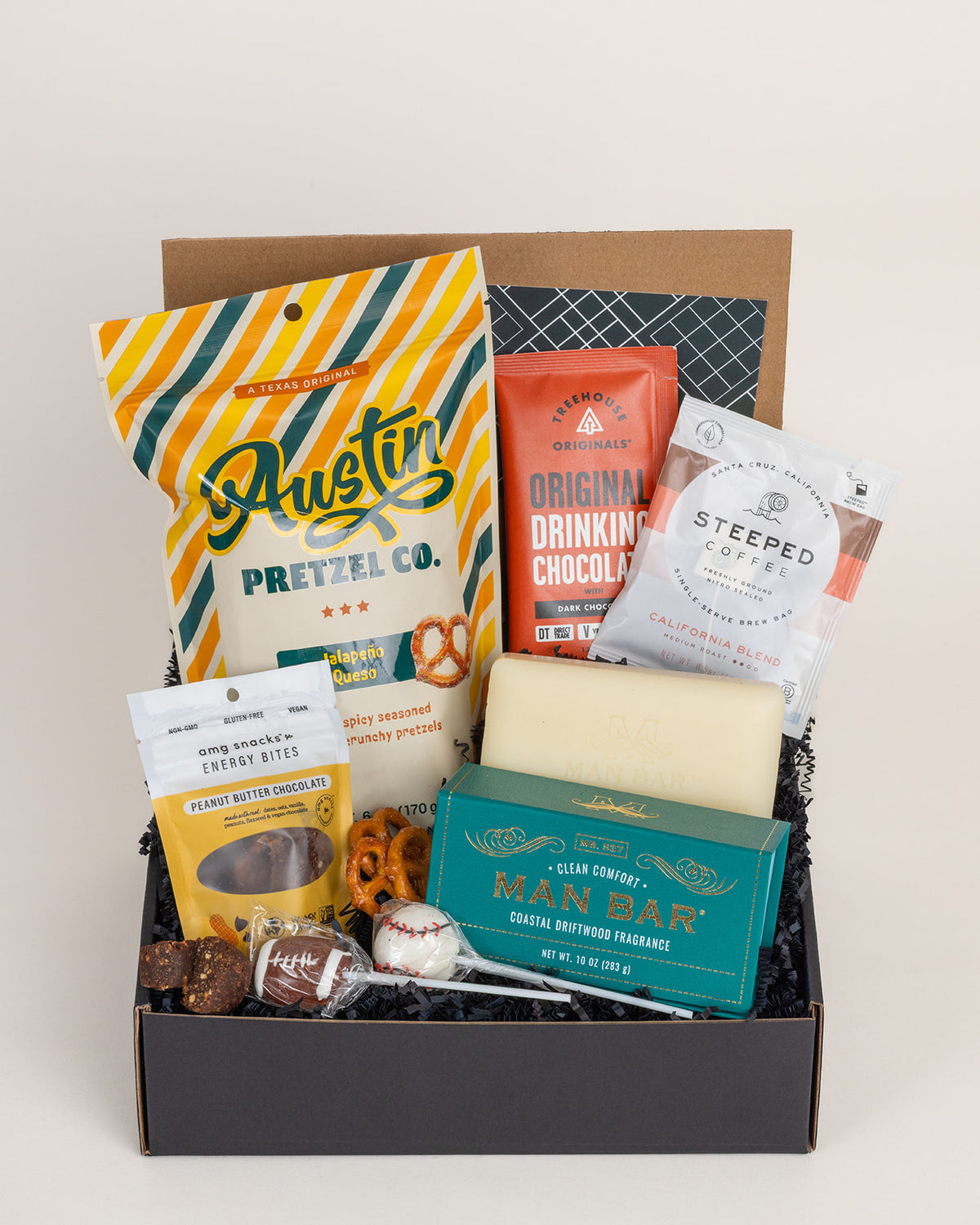 Gift box filled with Austin jalapeno pretzels, drinking chocolate, steeped coffee, energy bites, sports lollipops, and Man Bar soap.