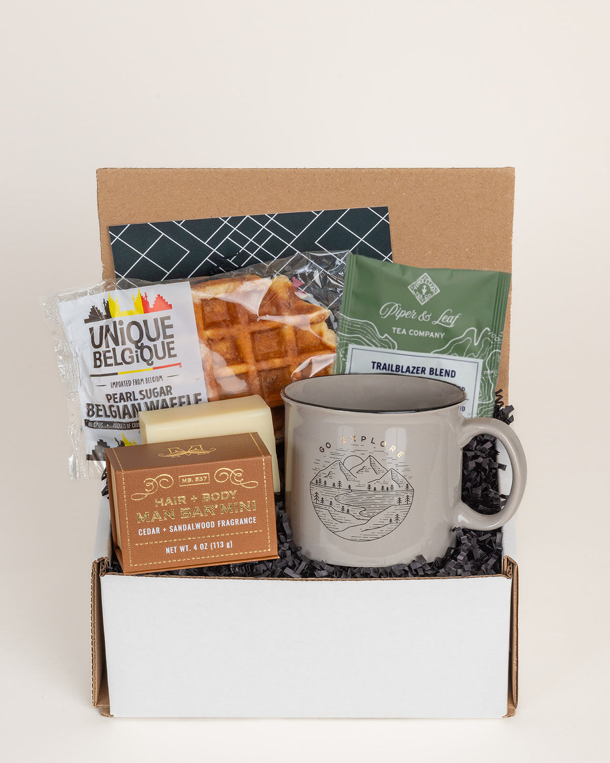 Gift box containing a Go Explore ceramic mug, Belgian waffle, Trailblazer tea, and a mini cedar sandalwood soap bar.