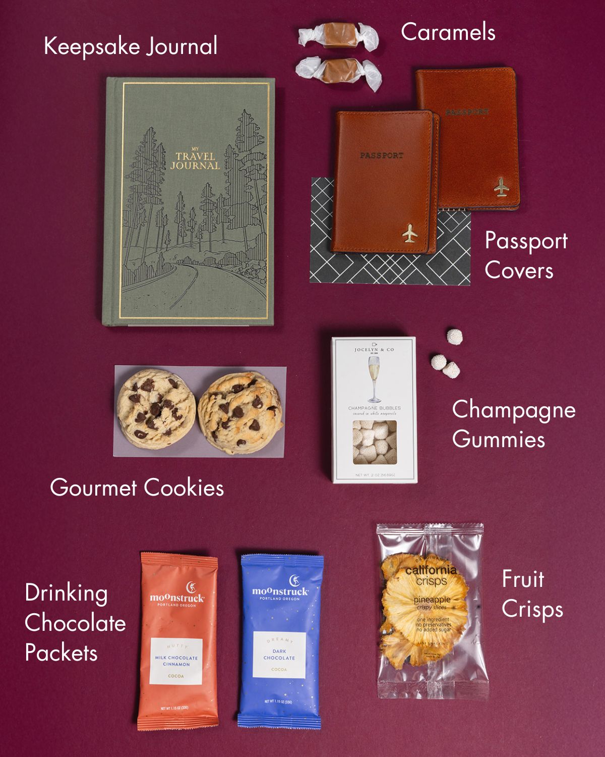 Travel gift box with a green journal, two leather passport covers, gourmet cookies, champagne gummies, chocolate, and fruit crisps.