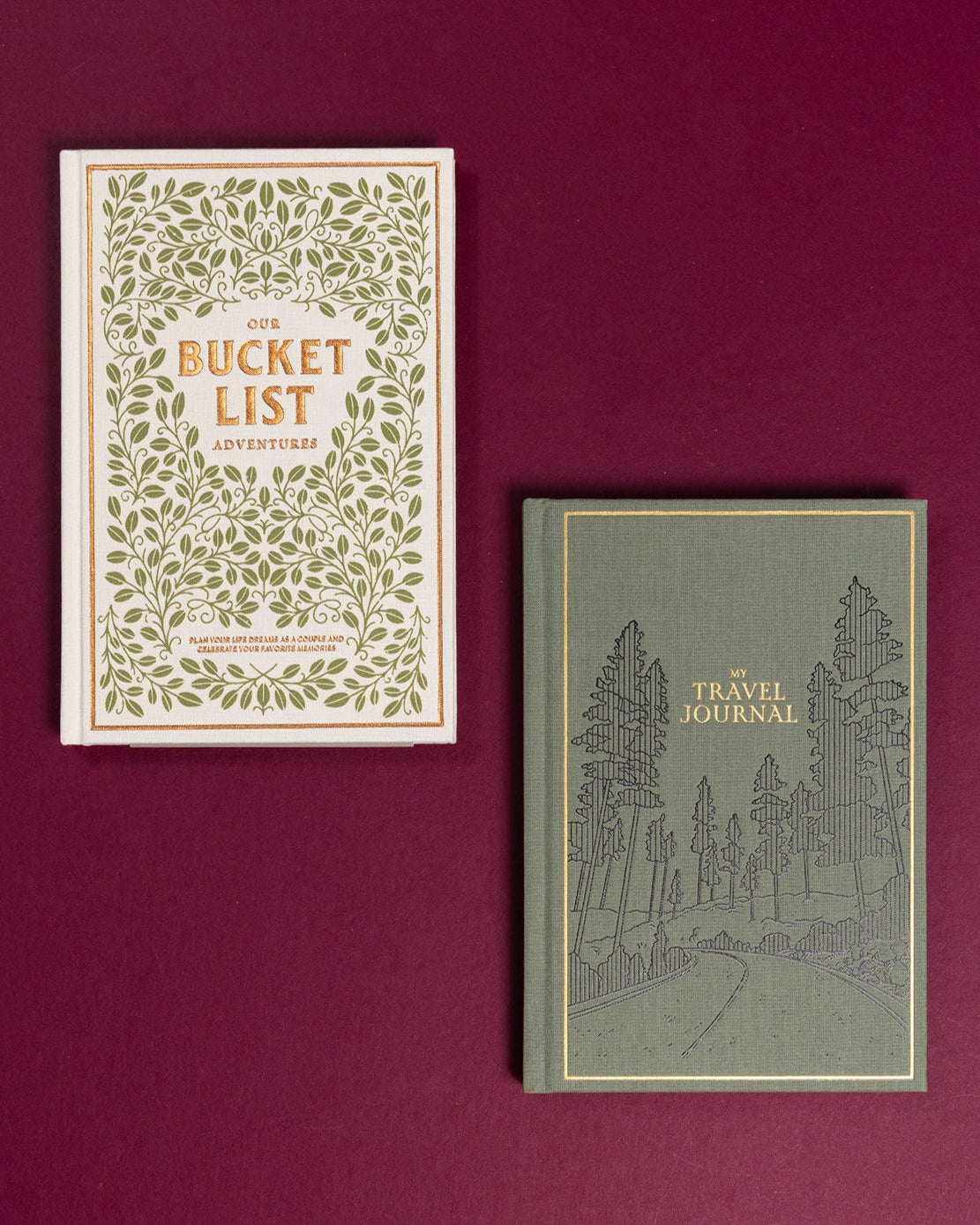 White bucket list journal with green leaf print and a sage green travel journal with gold foil forest illustration.