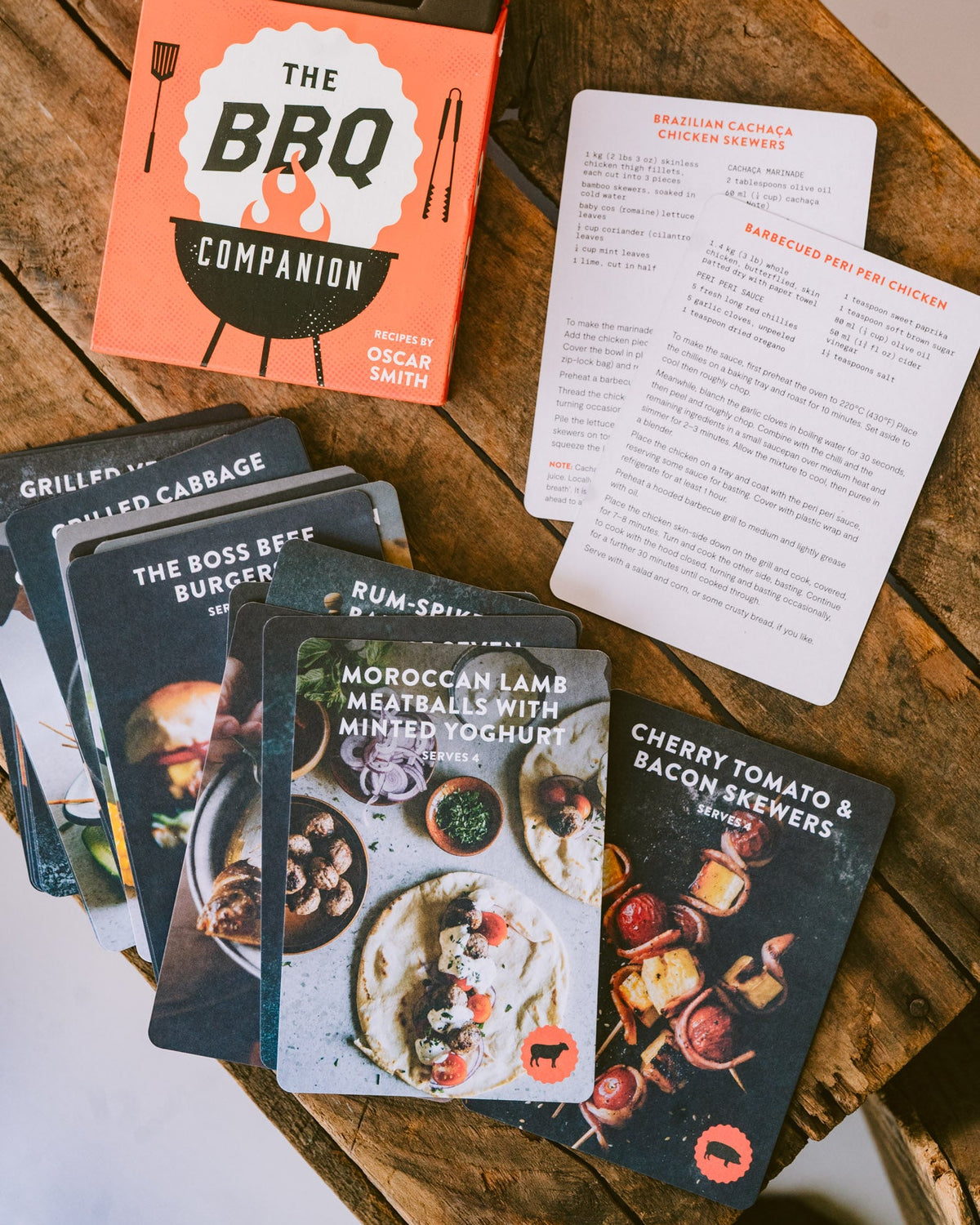 The BBQ Companion recipe cards and instruction sheets arranged on a rustic wooden surface.