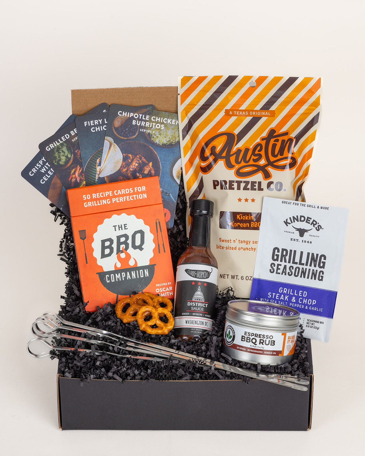 Grill Time gift box with stainless skewers, BBQ rub, hot sauce, seasoning, recipe cards, and pretzels in a black box.
