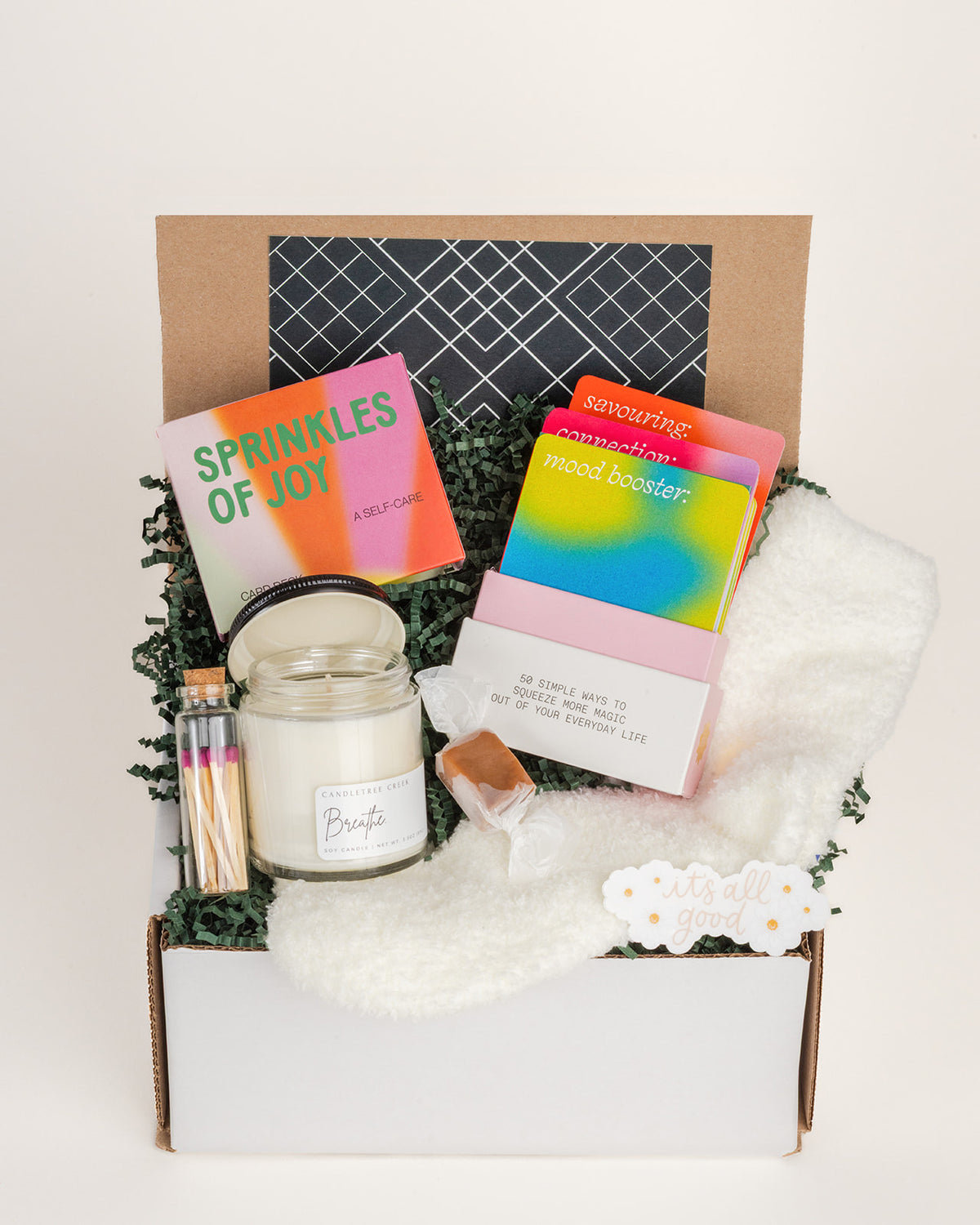 Me Time gift box filled with a Breathe soy candle, matches, colorful self-care cards, a caramel treat, and soft white socks.