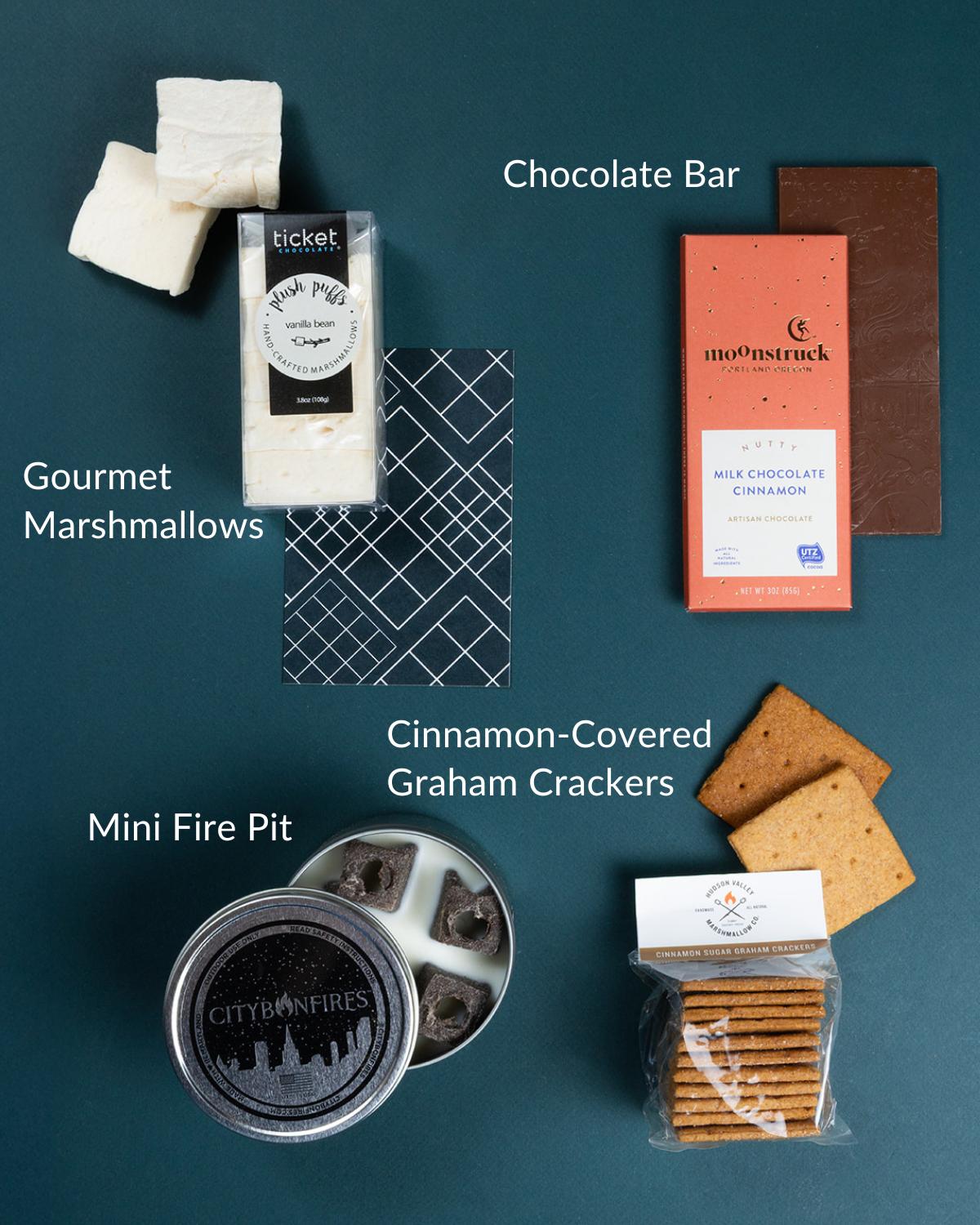 Mini s'mores kit with a round metal fire pit, gourmet vanilla marshmallows, a milk chocolate bar, and cinnamon graham crackers.