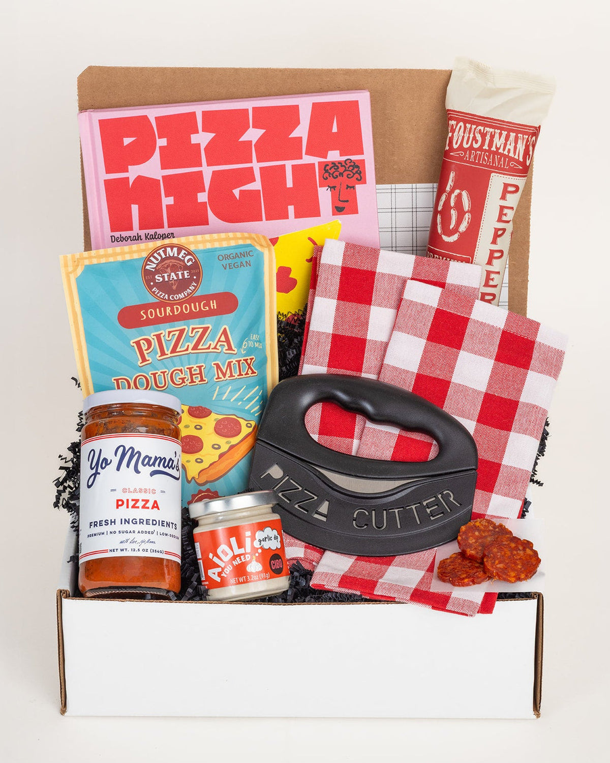 Pizza Night gift box featuring a cookbook, sourdough mix, pepperoni, sauce, garlic aioli, black pizza cutter, and red gingham towels.