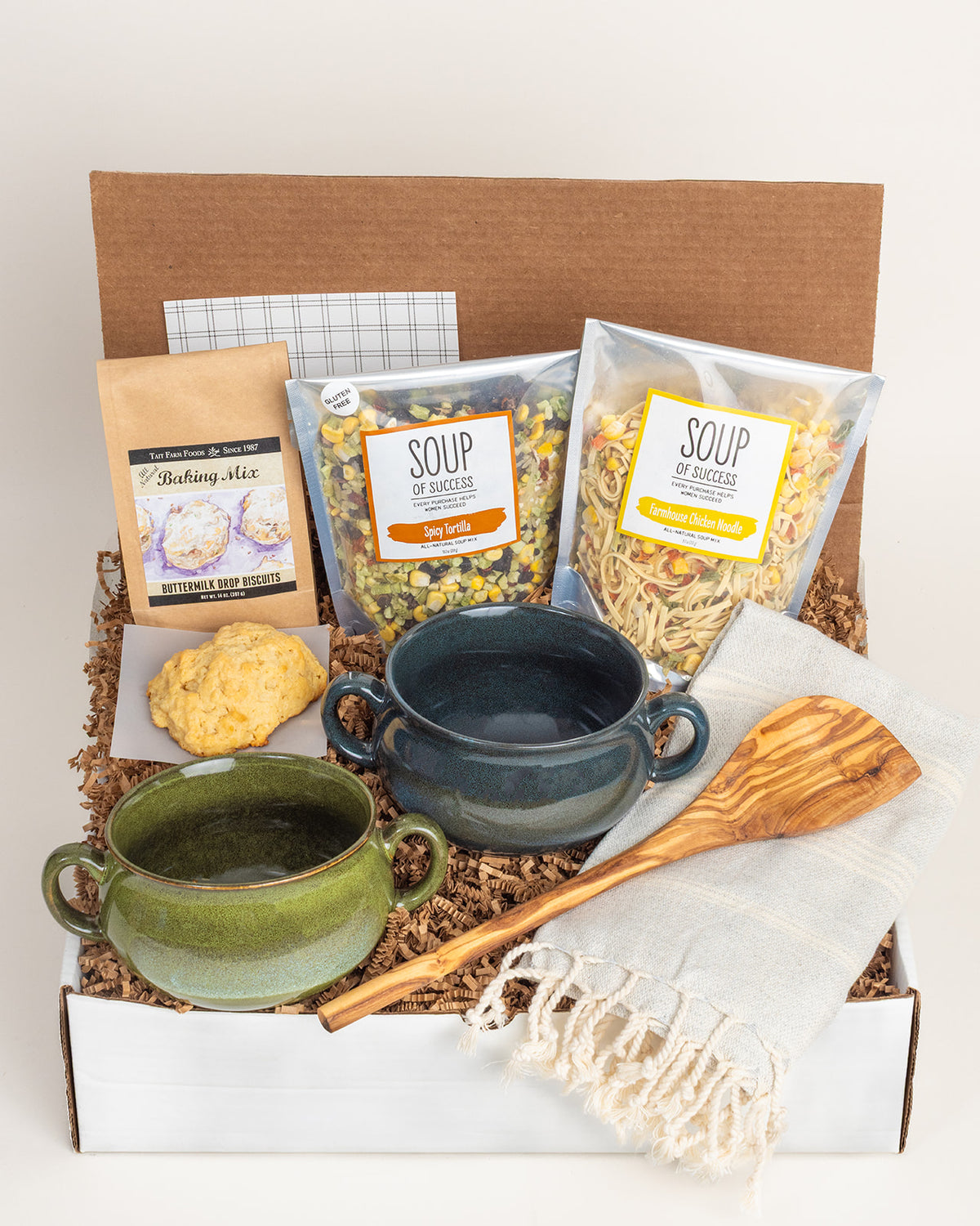 Gift box with two ceramic soup crocs, soup mixes, biscuit mix, an olive wood spoon, and a fringed Turkish towel.