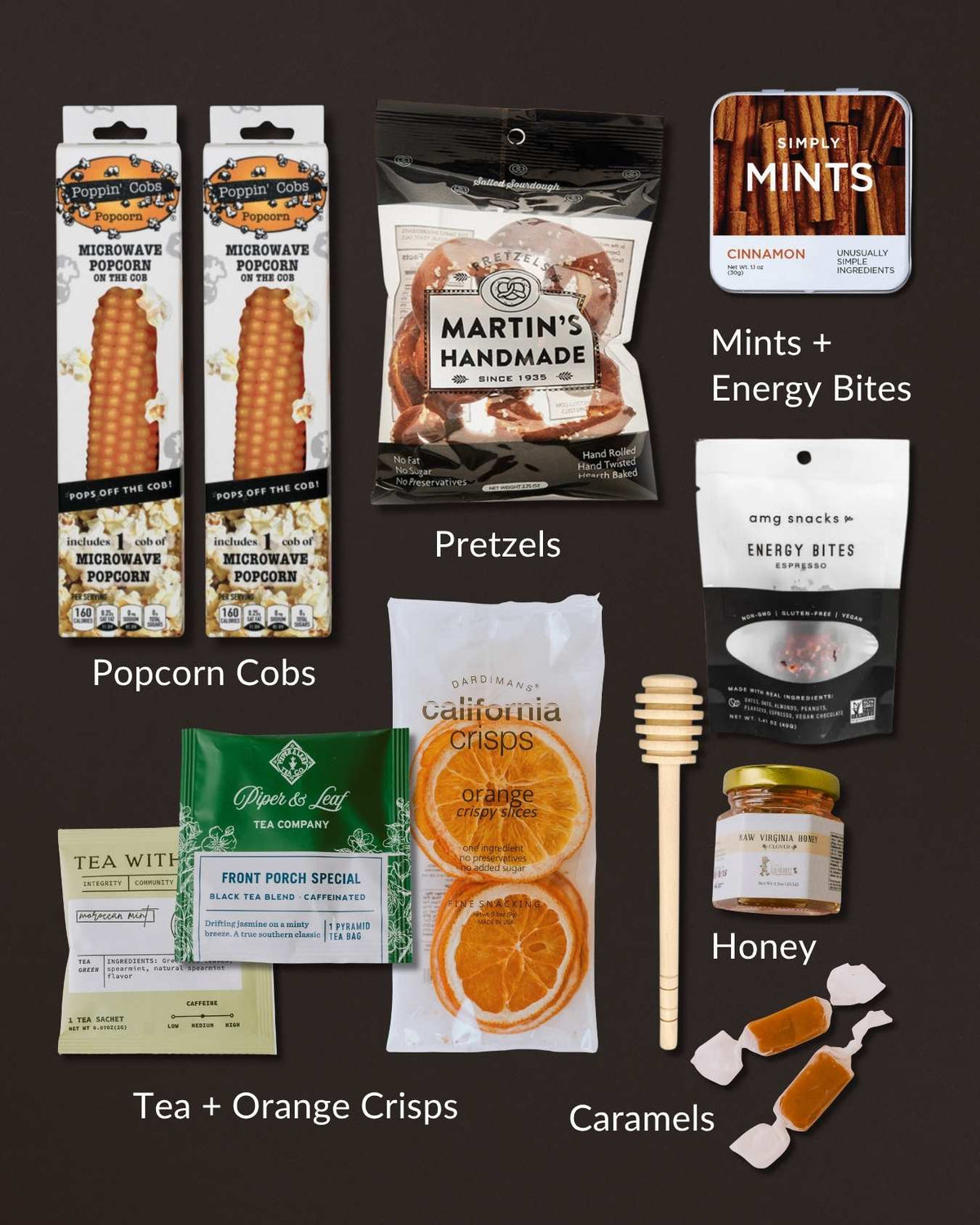 Tasty Morsels snack gift set featuring popcorn cobs, pretzels, energy bites, orange crisps, tea, honey with dipper, and caramels.