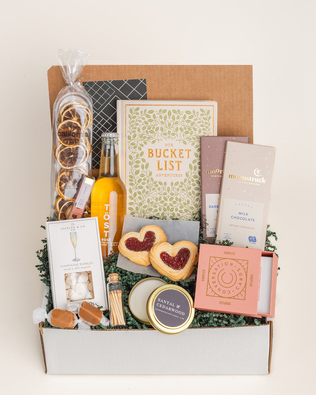 The Happy Couple gift box featuring snacks, a bucket list book, and a candle in a decorative cardboard box.