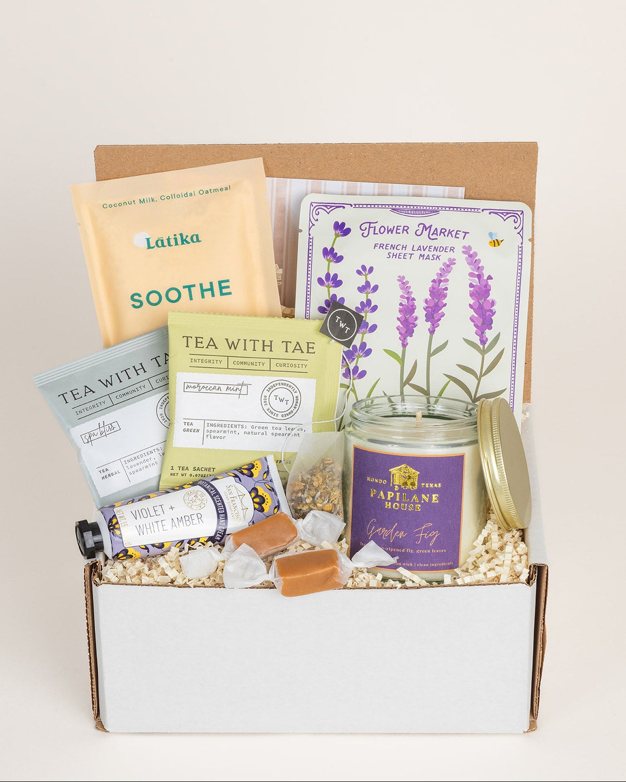 Gift box with tea, lavender products, and a candle on a white background