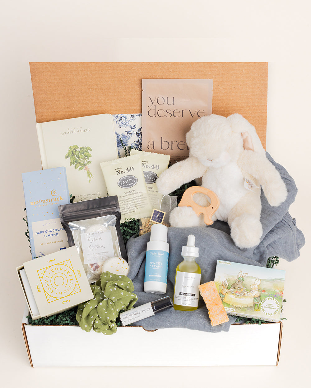 Welcome, Little One gift box featuring a plush bunny, skincare products, snacks, and a cozy blanket.