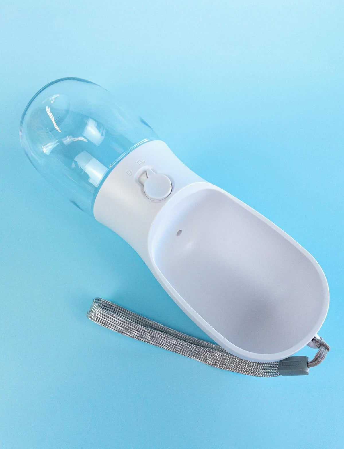 Portable white and clear plastic dog water bottle with a push-button dispenser and grey wrist strap on a blue background.
