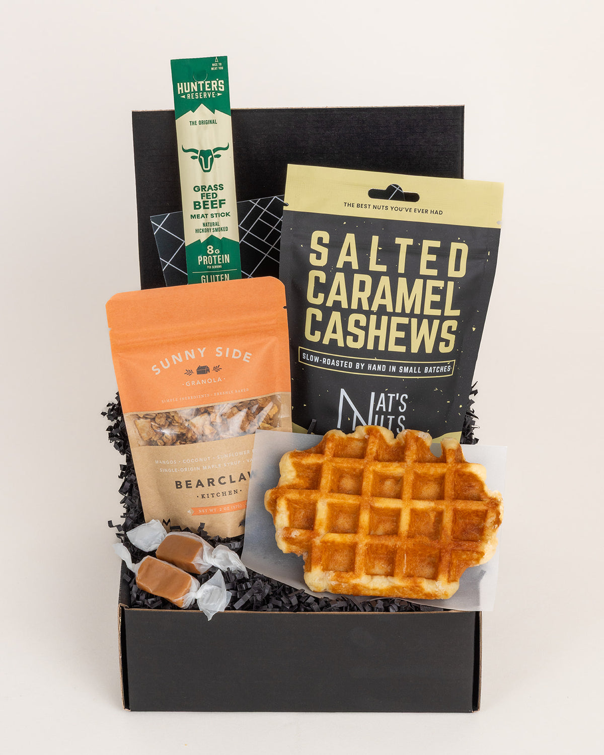 Mini Foodie gift box featuring a Belgian waffle, salted caramel cashews, granola, beef stick, and caramels in a black box.