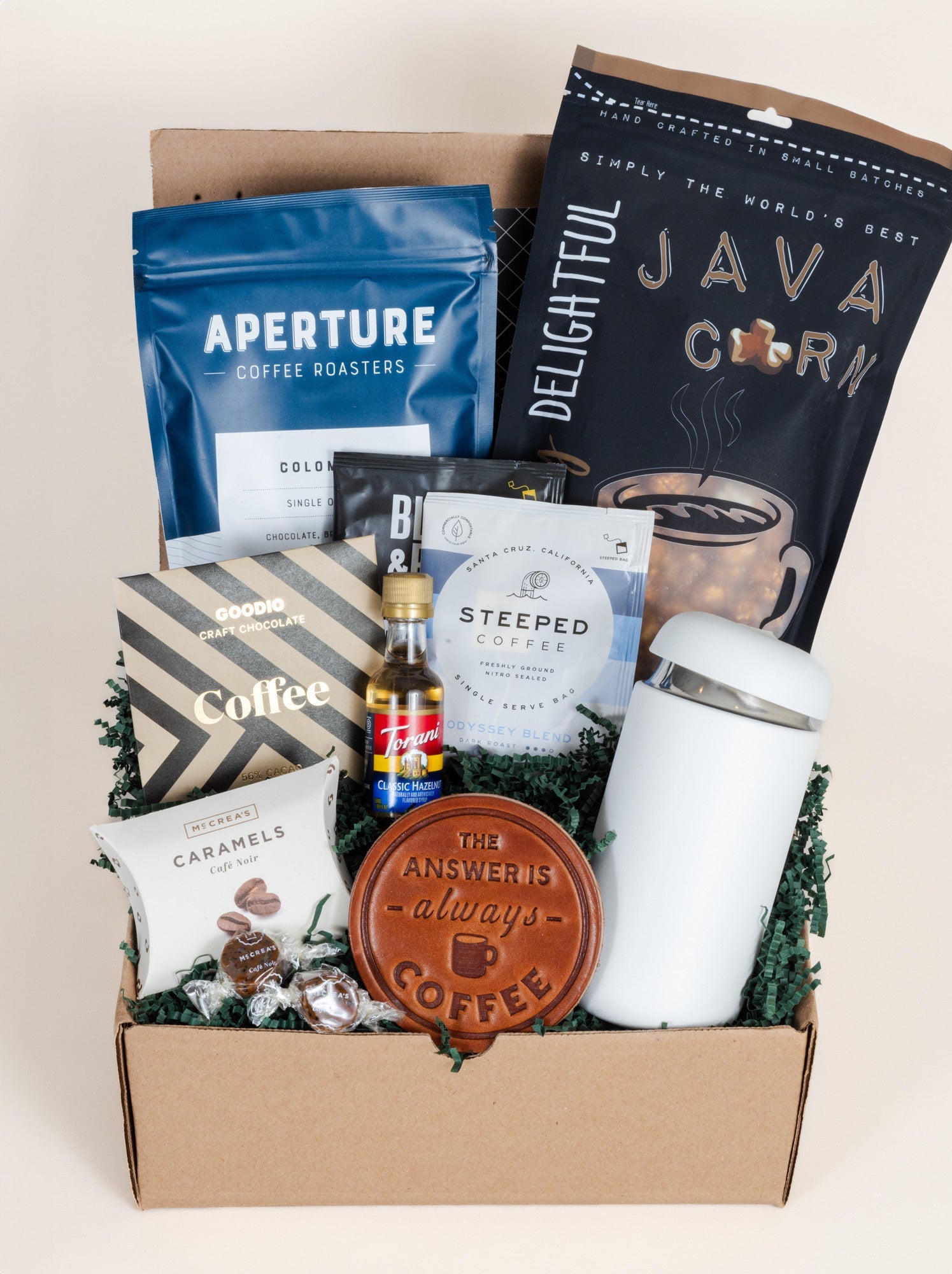 Coffee gift box with coffee bags, a tumbler, and other items on a light background